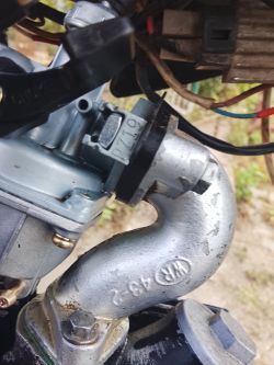 Zbliżenie na gaźnik PZ19 z rury dolotowej silnika małego motocykla lub motoroweru.