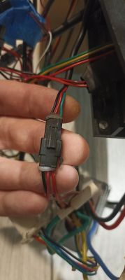 Ręka trzymająca wiązkę kabli z złączem w e-hulajnodze.