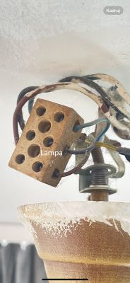 Zbliżenie na podłączenie elektryczne lampy sufitowej z kostką ceramiczną.