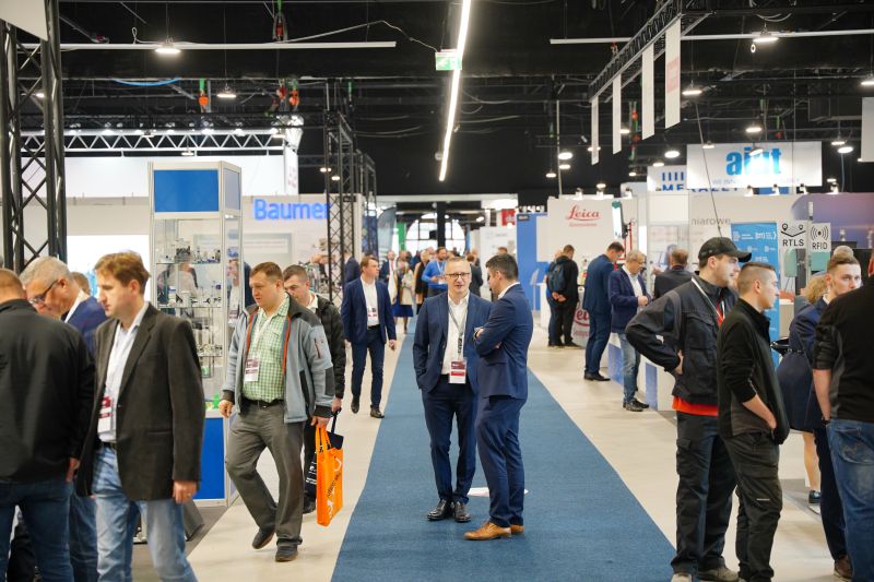 Industrial trade fair with attendees walking among various technology booths