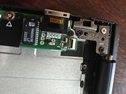 Zbliżenie na wnętrze laptopa ASUS z widoczną płytką drukowaną i złączem taśmy