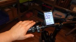Widok na kierownicę fatbike'a z wyświetlaczem LCD M5 i ręką na manetce.