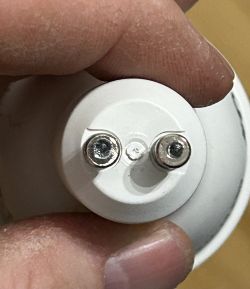 Close-up of the bottom part of a bulb with two visible wires and drill marks.