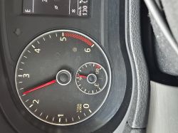 Zbliżenie na deskę rozdzielczą samochodu, w której widoczny jest wskaźnik obrotów silnika i temperatury cieczy chłodzącej.