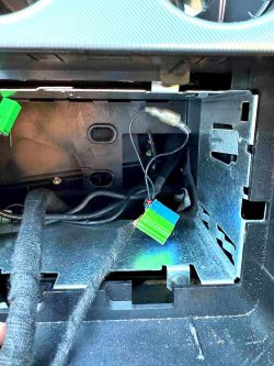 Wnętrze deski rozdzielczej samochodu z widoczną zielono-niebieską wtyczką.