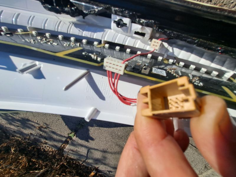 Close-up of LED tail light interior with wires and connector held by hand