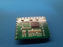 Close-up of a green PCB with an IC chip and SMD components on a blue work mat