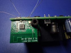 Close-up of a green PCB with an IC, soldered wires, and a capacitor on a blue surface