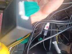 Zbliżenie na zielone przewody podłączane do czarnego modułu CAN bus w kokpicie auta