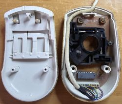 Interior of a disassembled computer mouse from an Amiga, with visible electronics and wires.