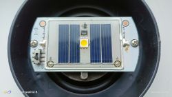 Zbliżenie na panel solarny lampki ogrodowej z osłoniętą elektroniką i włącznikiem.