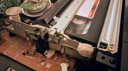 Kaseta VHS częściowo wysunięta z magnetowidu Philips VR1100 z widocznymi elementami mechanizmu