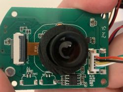 Electronic camera module with a visible lens and connected wires.
