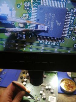 Mikrokontroler na płycie PCB pod mikroskopem z uszkodzonym elementem.