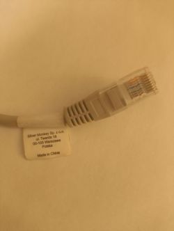 Przewód sieciowy z przezroczystą końcówką RJ45 oraz etykietą z informacjami o producencie.