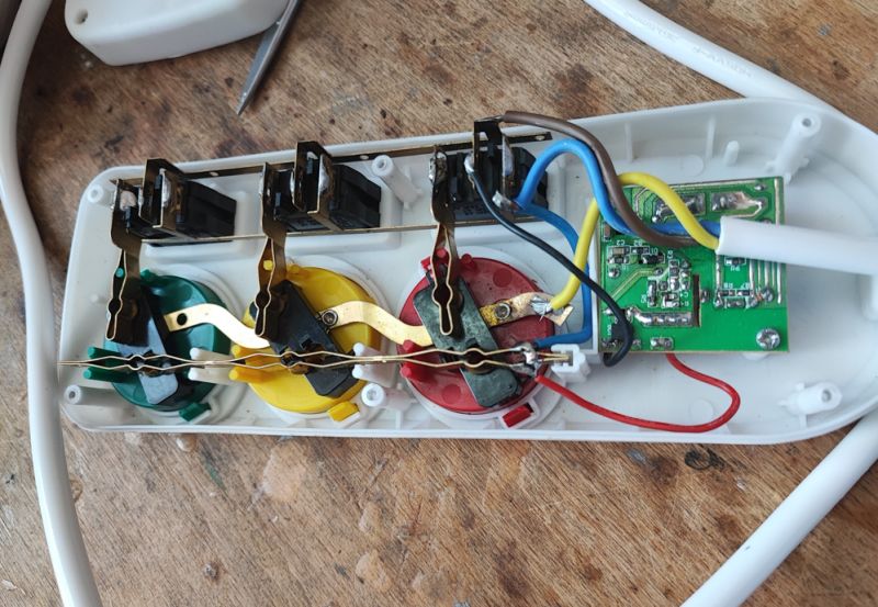 Wnętrze listwy zasilającej z kolorowymi gniazdami i przewodami.