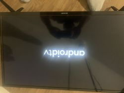 Telewizor Sharp wyświetlający odwrócony napis „Android” na czarnym ekranie.