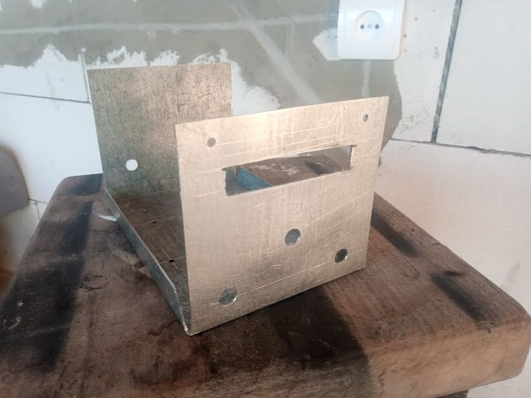 Metal enclosure with holes and rectangular cutout on a wooden workbench