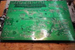 Spód dużej zielonej płyty PCB wyjętej ze starego switcha sieciowego, widoczne ślady zabrudzeń i osadów.