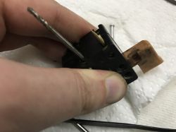 Repairing the Switch of an Old Celma Drill Person holding a disassembled switch of a device on a paper towel.