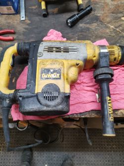 Młotowiertarka DeWalt D25723 leży na różowej szmatce na stole roboczym.