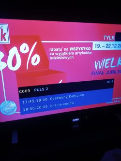 Wyświetlacz telewizora pokazujący program telewizyjny z reklamą zniżki.
