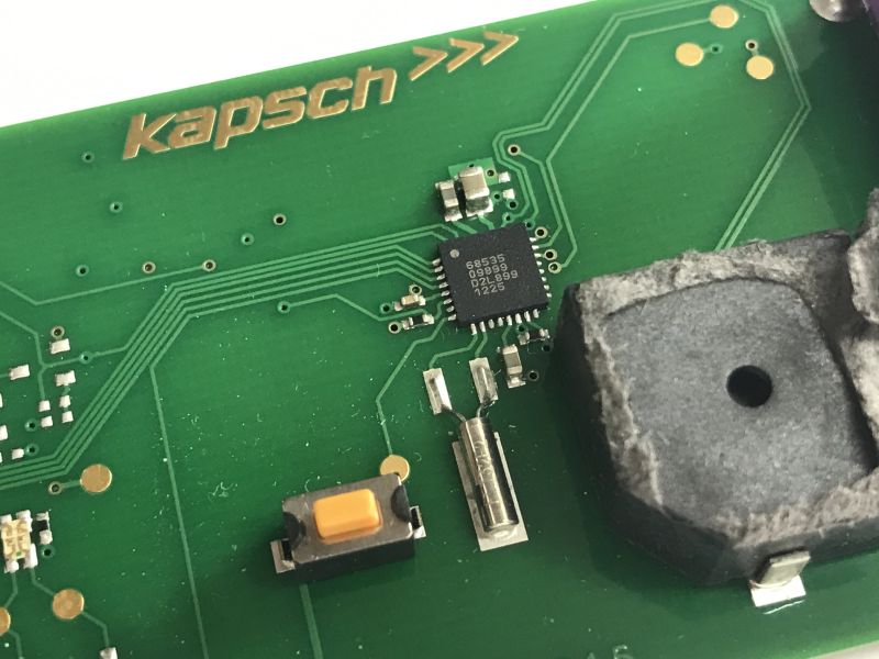 Close-up of a Kapsch PCB with an IC, a push button, and a buzzer