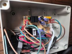 Wnętrze obudowy urządzenia elektronicznego z widocznymi przewodami, płytką drukowaną i komponentami.