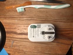 Toothbrush and adapter with Silvergear logo on a wooden table.