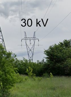 Słup energetyczny 30 kV na tle nieba i roślinności, z zaznaczoną odległością między przewodami.