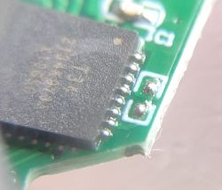 Close-up of an integrated circuit on a green printed circuit board.