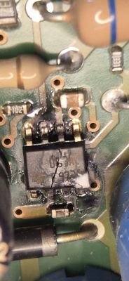 Makrofoto PCB z pękniętym układem SMD i śladami przypalenia wokół wyprowadzeń