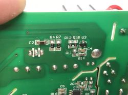 Zbliżenie na płytkę PCB z widocznymi elementami SMD, oznaczeniami rezystorów i kondensatorów.