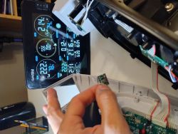 Osoba trzymająca mały moduł RF przed wyświetlaczem stacji pogodowej.