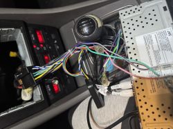 Wnętrze samochodu z demontowaną konsolą i widocznymi przewodami.