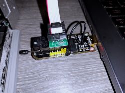 PCB with ribbon cable and wires connected, next to a USB port and a lit red LED