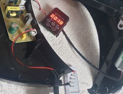 Widok wnętrza urządzenia z otwartą pokrywą, widoczna płytka elektroniki oraz panel sterowania z wyświetlaczem.