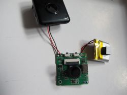 Electronic Circuit Board with Battery and Casing A printed circuit board with electronics, a battery, and a black plastic casing on a white background.