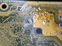 Close-up of a motherboard with visible traces and soldering holes.