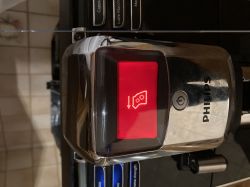 Wyświetlacz ekspresu Philips pokazuje czerwoną ikonę jednostki zaparzającej i strzałkę w dół.