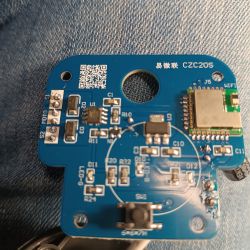 A printed circuit board with electronic components on a denim fabric background.
