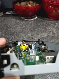 Wnętrze urządzenia elektronicznego z widocznymi elementami na zielonej płytce drukowanej.