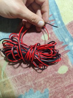 Czarny i czerwony kabel trzymany w dłoni, z nawiniętą częścią.