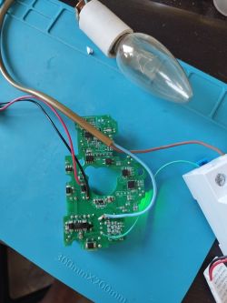 Printed circuit board with electronic components and a light bulb on a blue service mat.