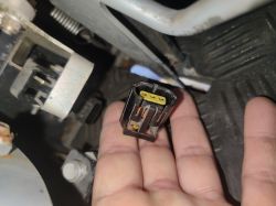 Dłoń trzyma czarną wtyczkę elektryczną z żółtą wkładką przy elementach mechanicznych
