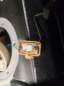 Zbliżenie na plastikową obudowę elementu z przewodami i metalowym ramieniem we wnętrzu samochodu.