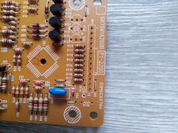 Fragment płytki PCB z rezystorami, diodami i niebieskim kondensatorem; widoczne oznaczenia „6870W1A200B”.