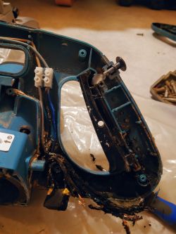 Widok wnętrza rękojeści piły ukosowej Makita LS1018L z widocznymi przewodami i połączeniami elektrycznymi.