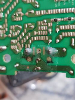 Close-up of a damaged circuit board with a scorched area.