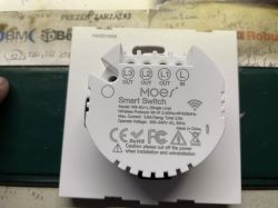 Moes smart switch with labeled terminals and technical specifications visible on the cover, viewed from above.